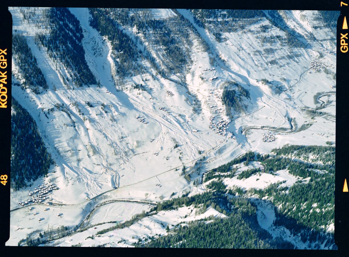 Zwischen Niederwald (links), Blitzingen und Selkingen haben drei Lawinen die Kantonsstrasse und die Bahnlinie überflossen. Zwei Strassenabschnitte und ein Bahnabschnitt sind durch Galerien geschützt, aber an drei anderen Stellen wurden die Verkehrswege blockiert. Ganz am rechten Bildrand ist die Bieligertal-Lawine, welche 7 Gebäude zerstört und weitere 9 beschädigt hat, noch knapp erkennbar. Aufnahmerichtung: SSE, 25. 02. 1999, 16:00; Titel der Aufnahme: BLITZINGEN / WILER; Goms, Wallis Kameramodell: Expression 12000XL